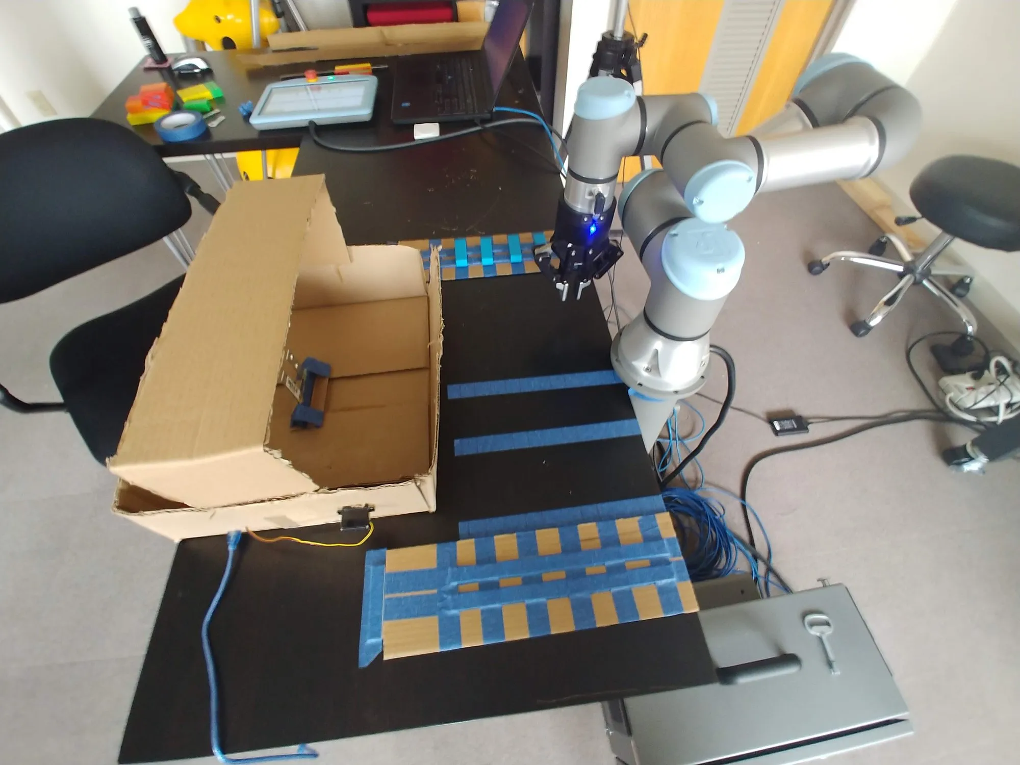 The box and grid from the arm's side, gripper tilted toward the table.