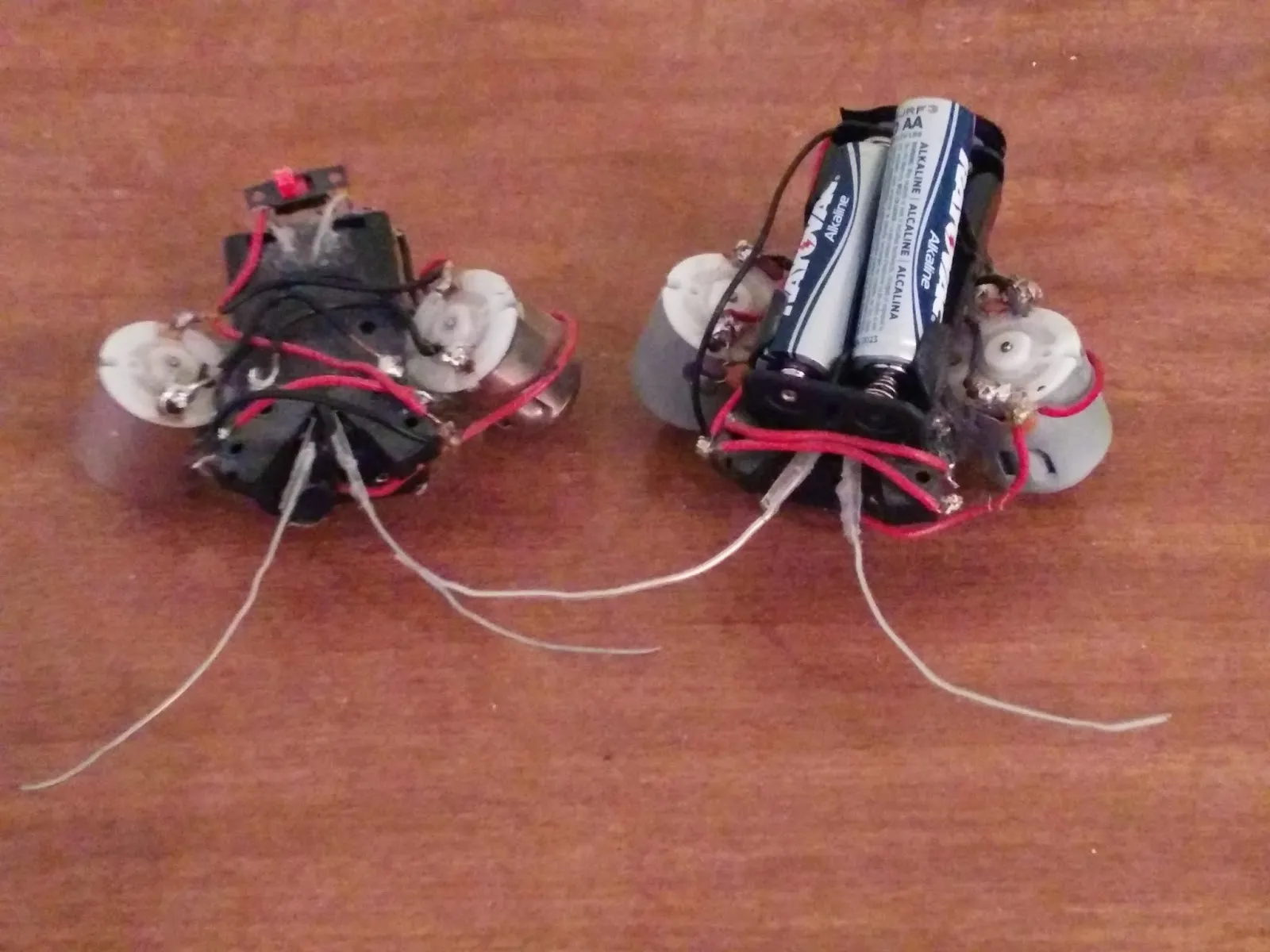 Two hand-built BEAM beetle robots side by side on a white table.