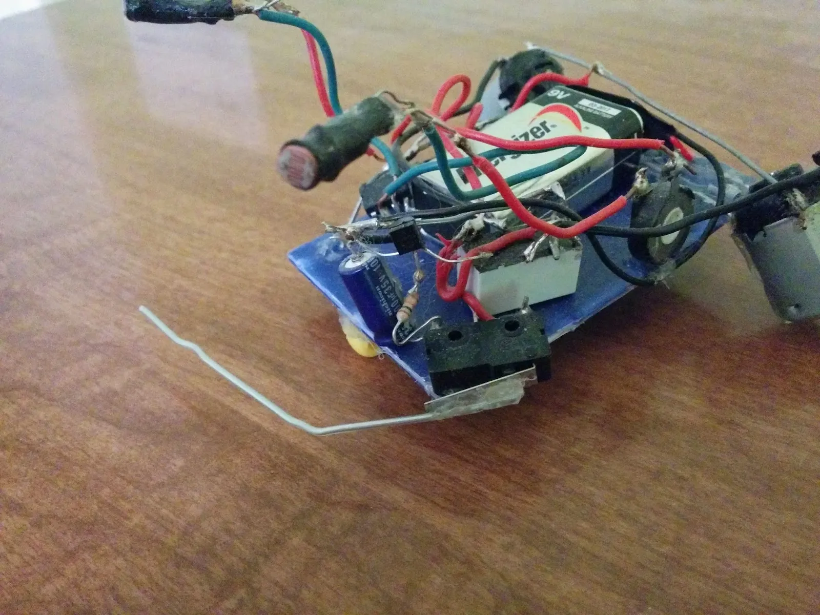 Herbie the Photovore: 9V battery on a blue plastic chassis, photoresistor eyes on stalks, wire whisker out front.