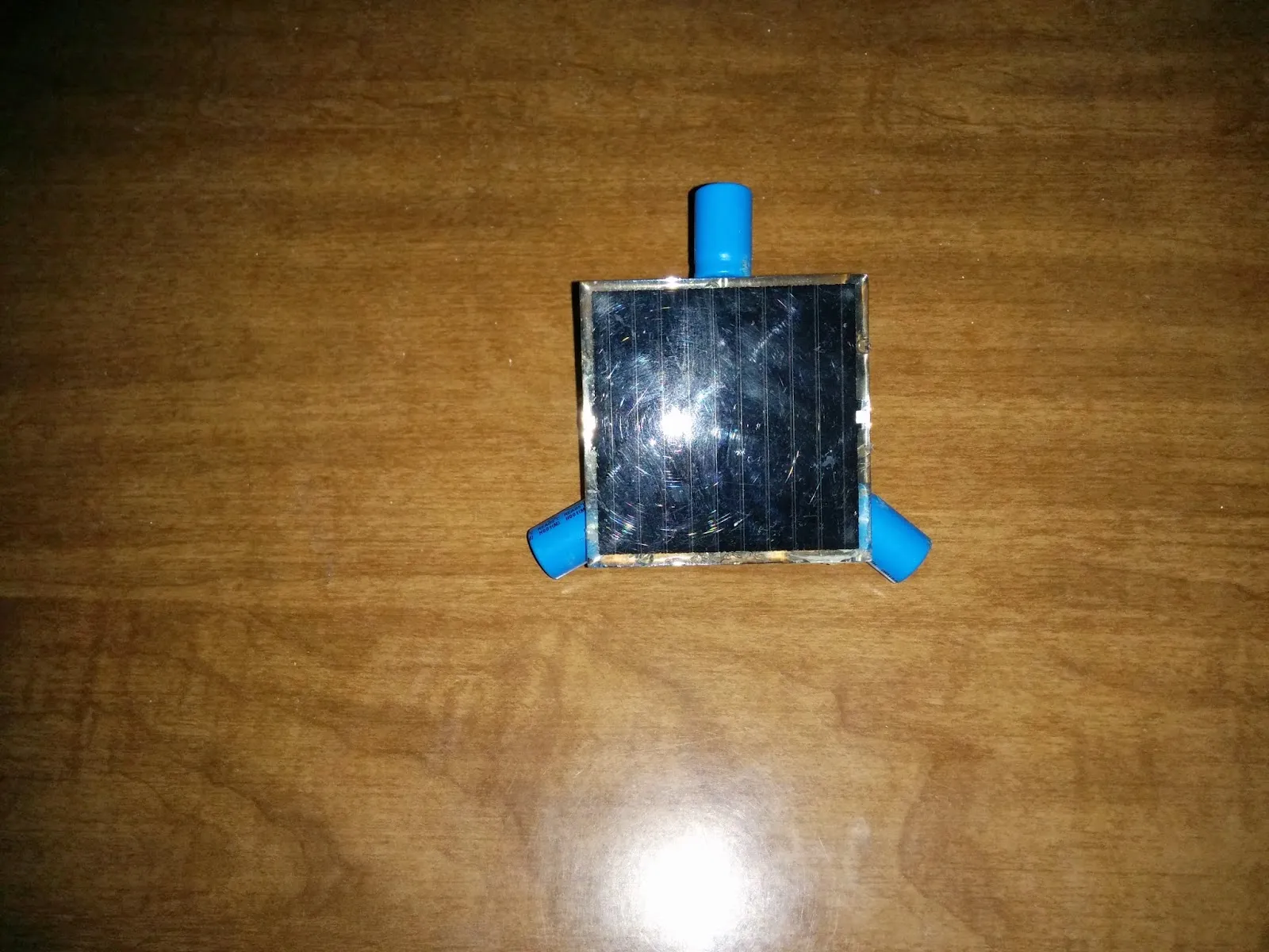 Top view of the Symet: a square solar cell balanced on three blue capacitor feet.