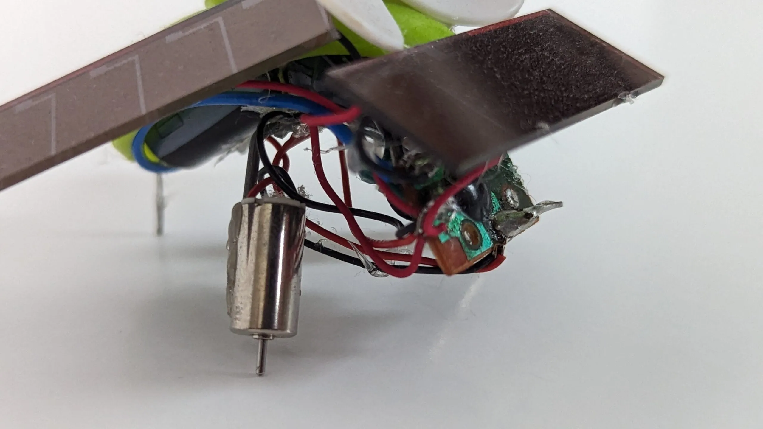 Macro of SymFlower's underside: pager motor, glue blobs, and point-to-point wiring doing structural duty.