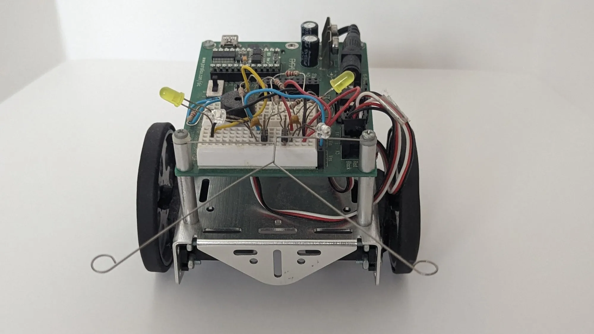 The BOE-Bot head on: BASIC Stamp board over the breadboard, yellow LEDs up, whisker wires curling out to both sides.