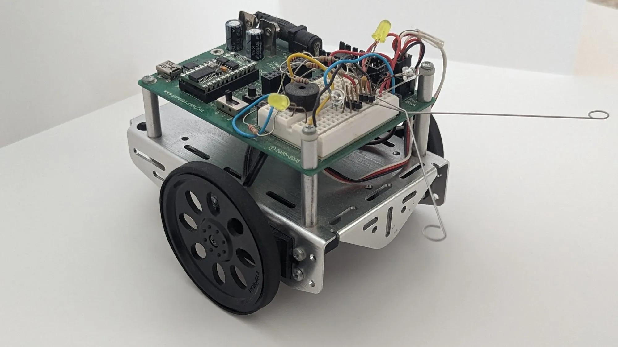 Three-quarter view of the BOE-Bot from the right, both whiskers spread and the servo leads tucked under the board.