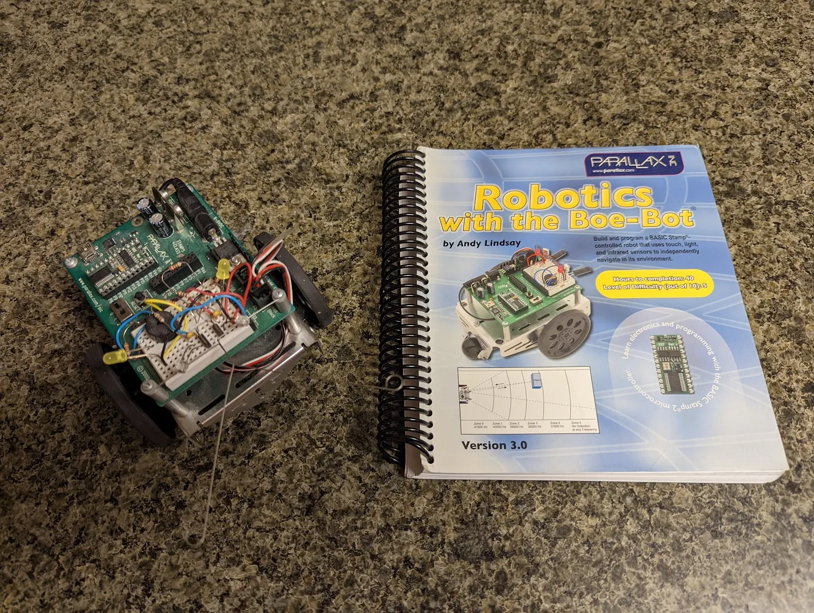 The BOE-Bot beside Andy Lindsay's "Robotics with the Boe-Bot," the book behind the merit badge.