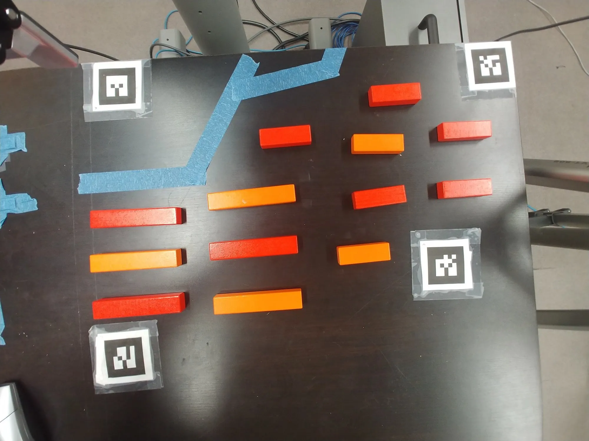 Red and orange blocks laid out in rows at assorted angles on the taped table, tags at the corners.