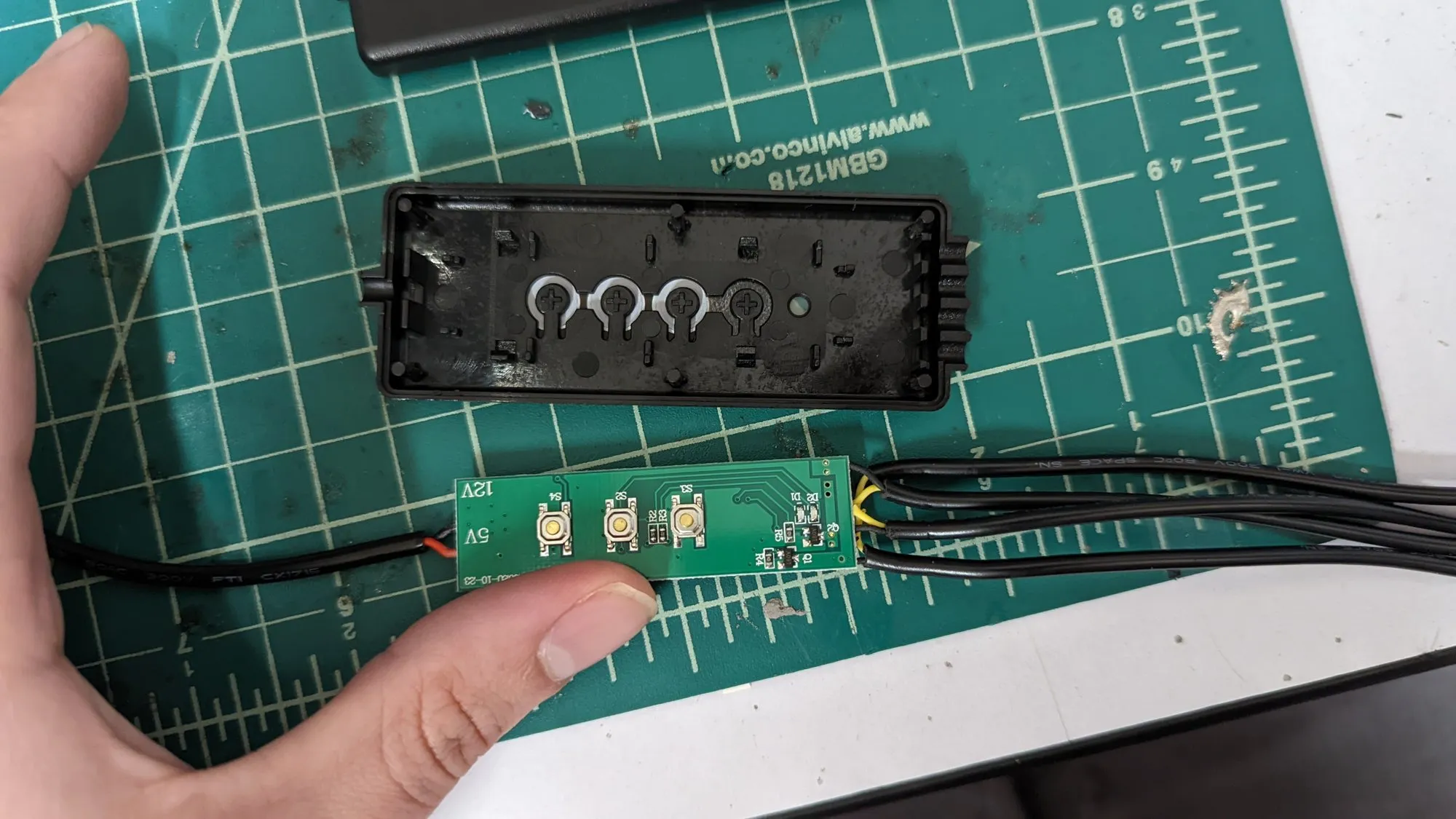The button side of the controller PCB held below the open shell: three tactile switches labeled S4, S2, and S3, two small LEDs, and 12V and 5V silkscreen at one end.