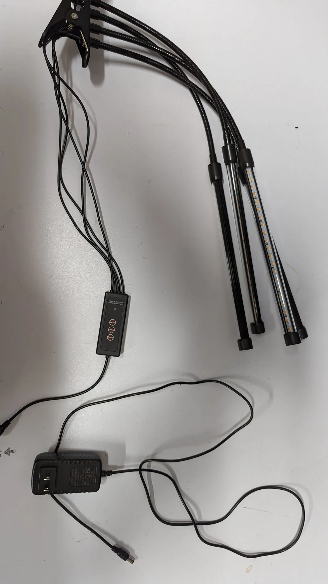 The stock grow light laid out: wall wart, inline controller with three buttons, and the four flexible arms bundled together.