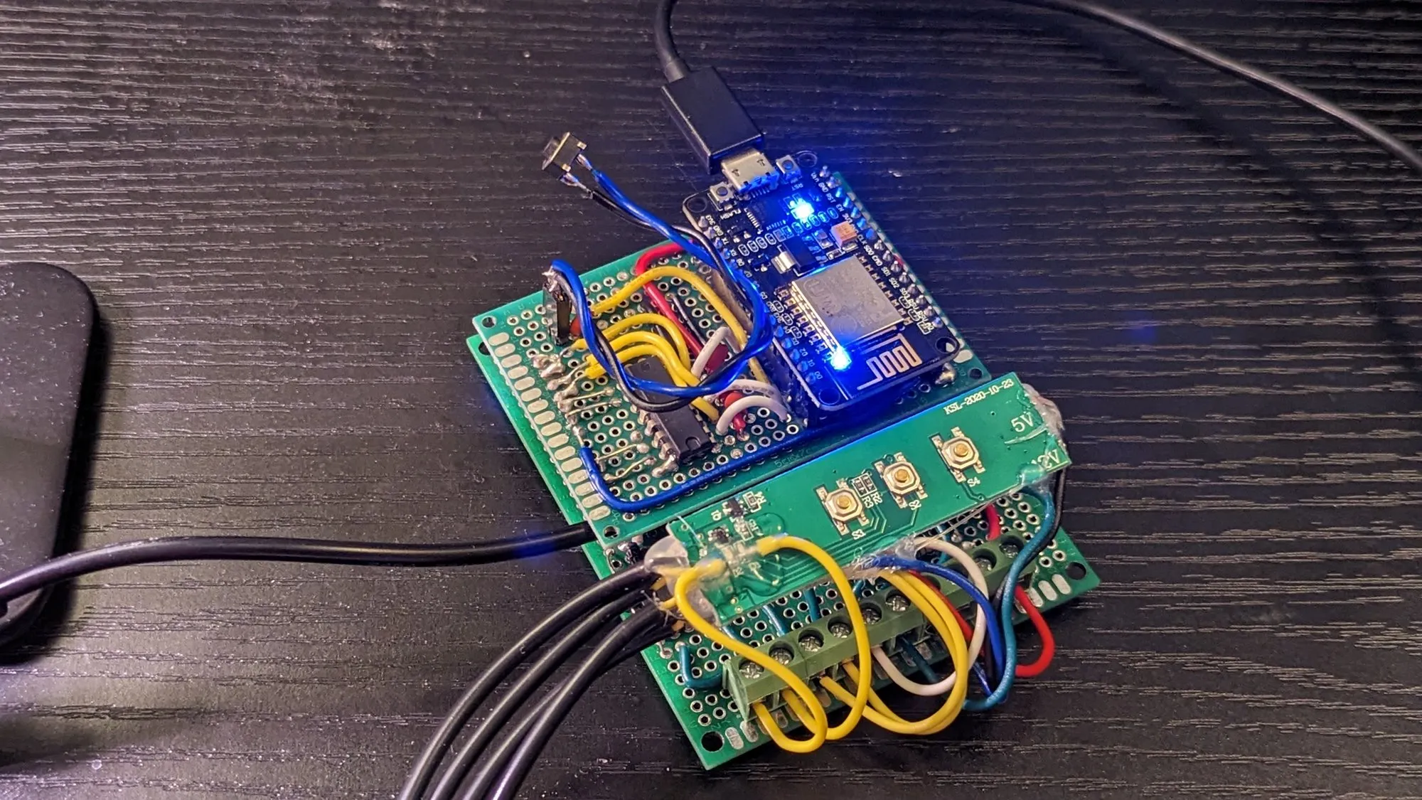 The board stack on a desk, wired to the grow light and powered, the NodeMCU's blue LED lit.