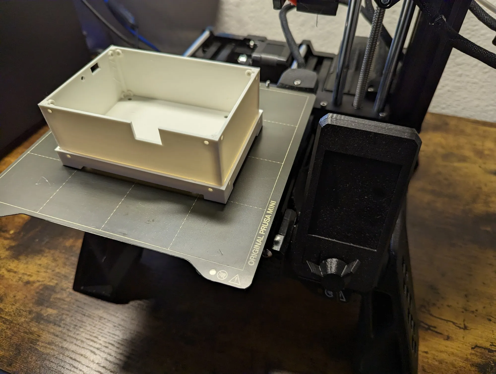 A white box, open side up, freshly printed on the Prusa Mini bed.