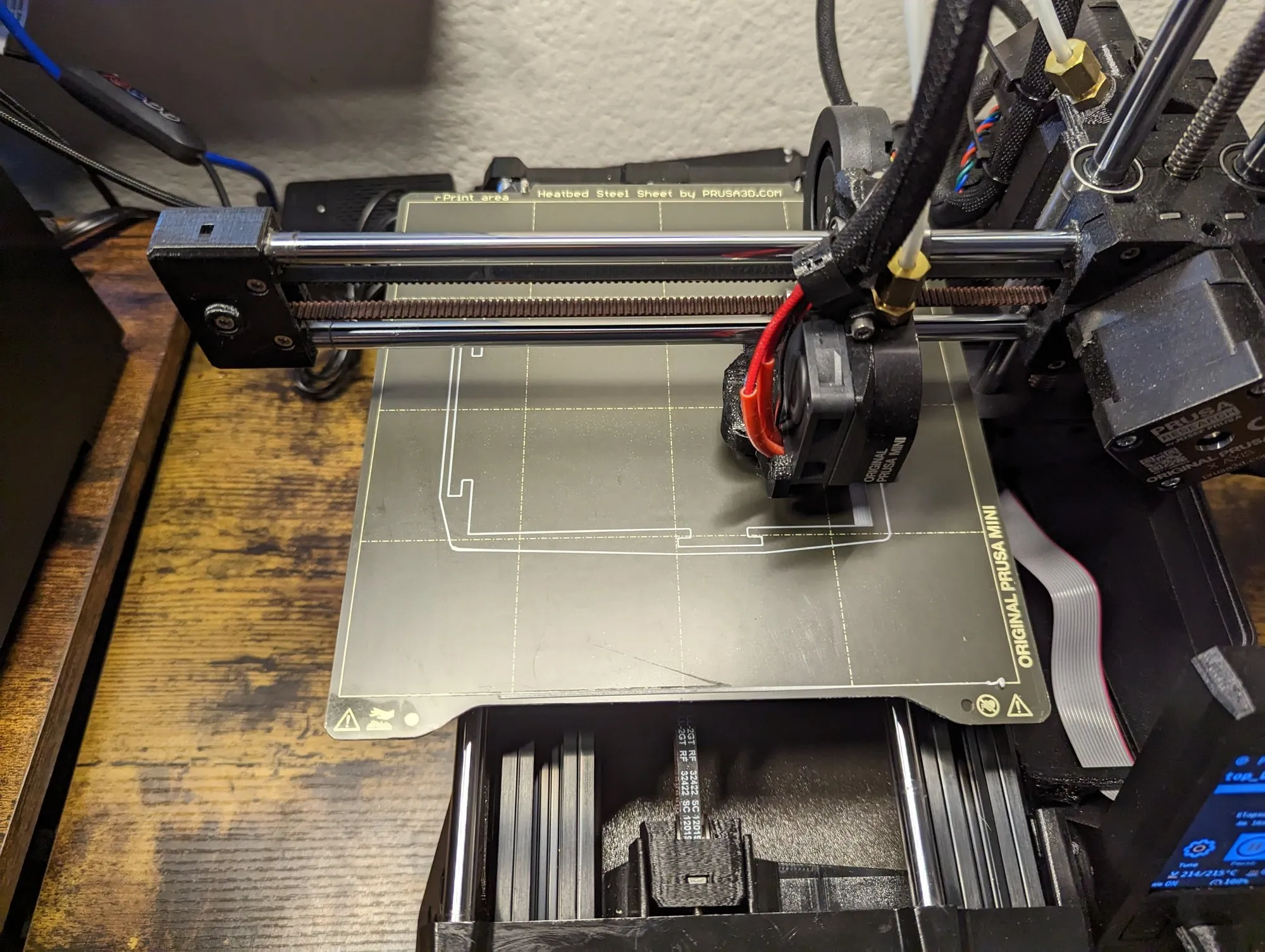 The Prusa Mini mid-print, the lid taking shape on the bed.