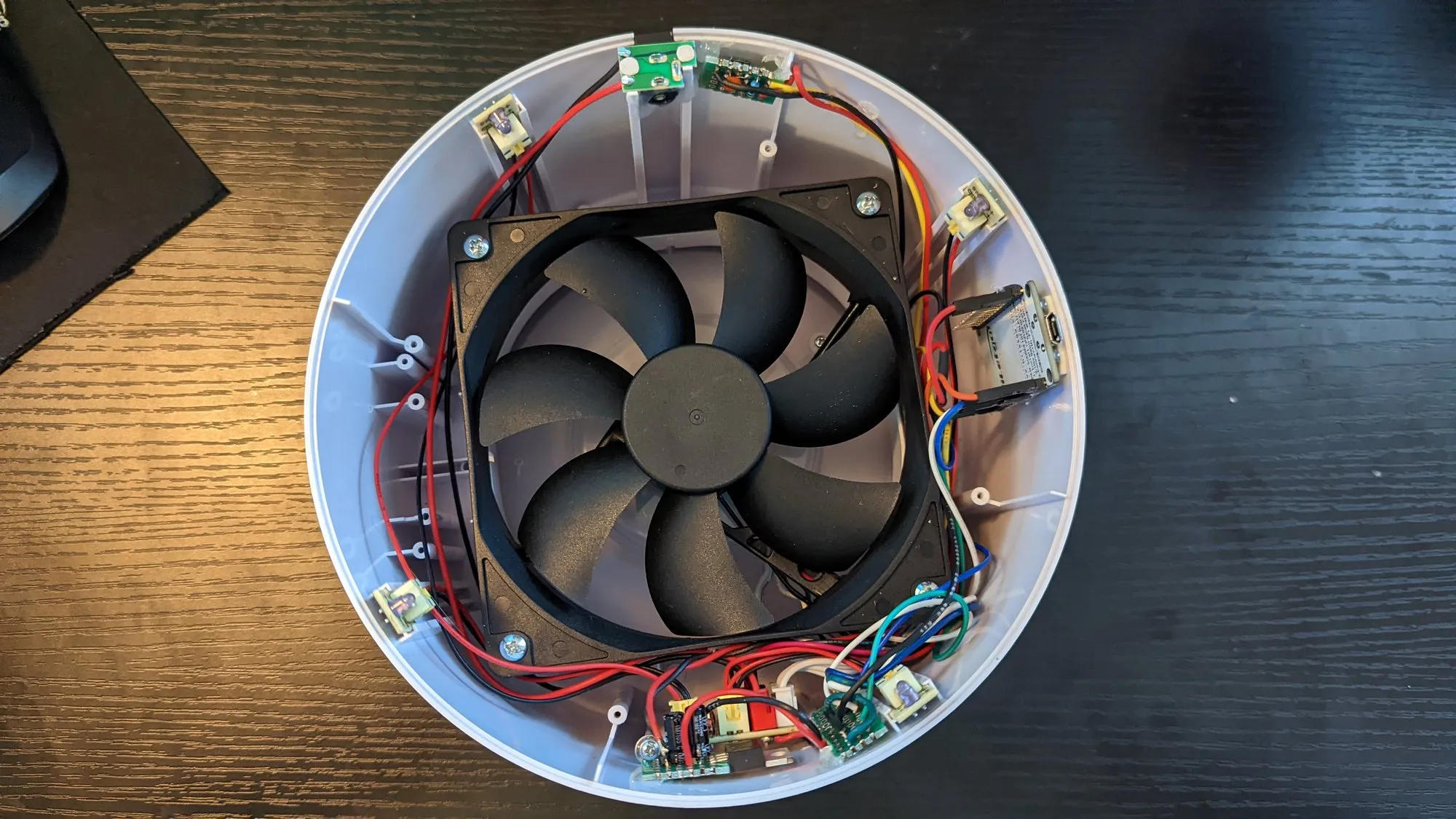 The reworked guts in February 2023, top down: the fan centered, the LED ring boards around the rim, a NodeMCU flat against the wall with blue and yellow jumpers.