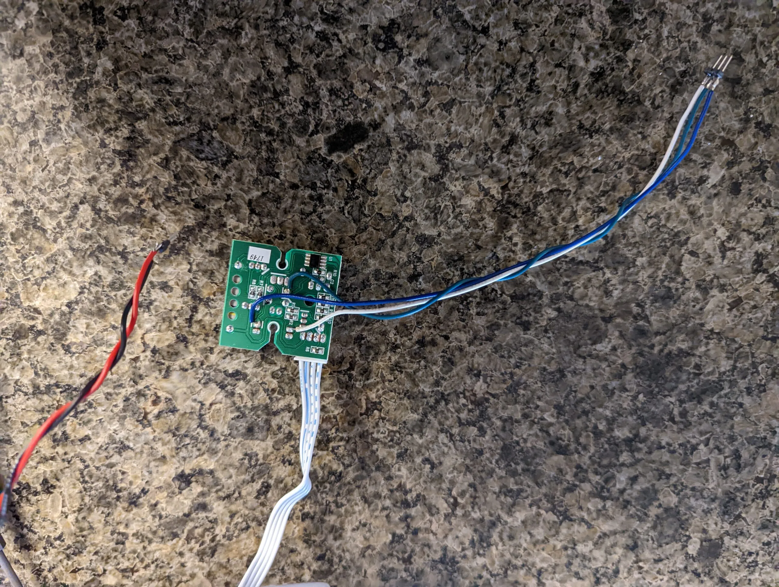 Blue and white signal leads soldered onto the board's pads and flying out to a header, the ribbon cable still attached and a red and black power pair off to the side.