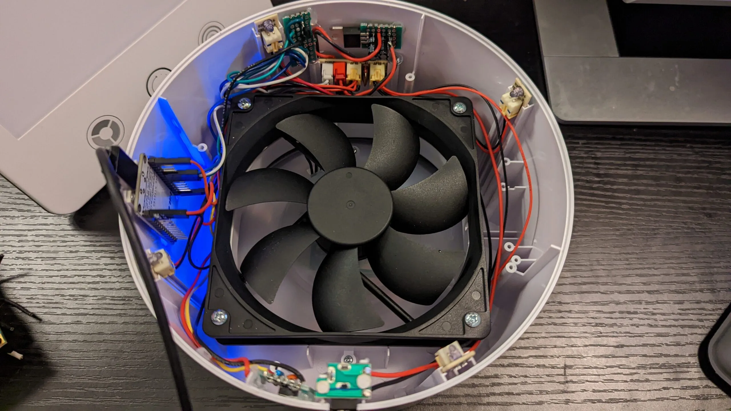 Still open and powered for flashing: a USB cable running to the NodeMCU, the ring LEDs glowing blue under the fan.