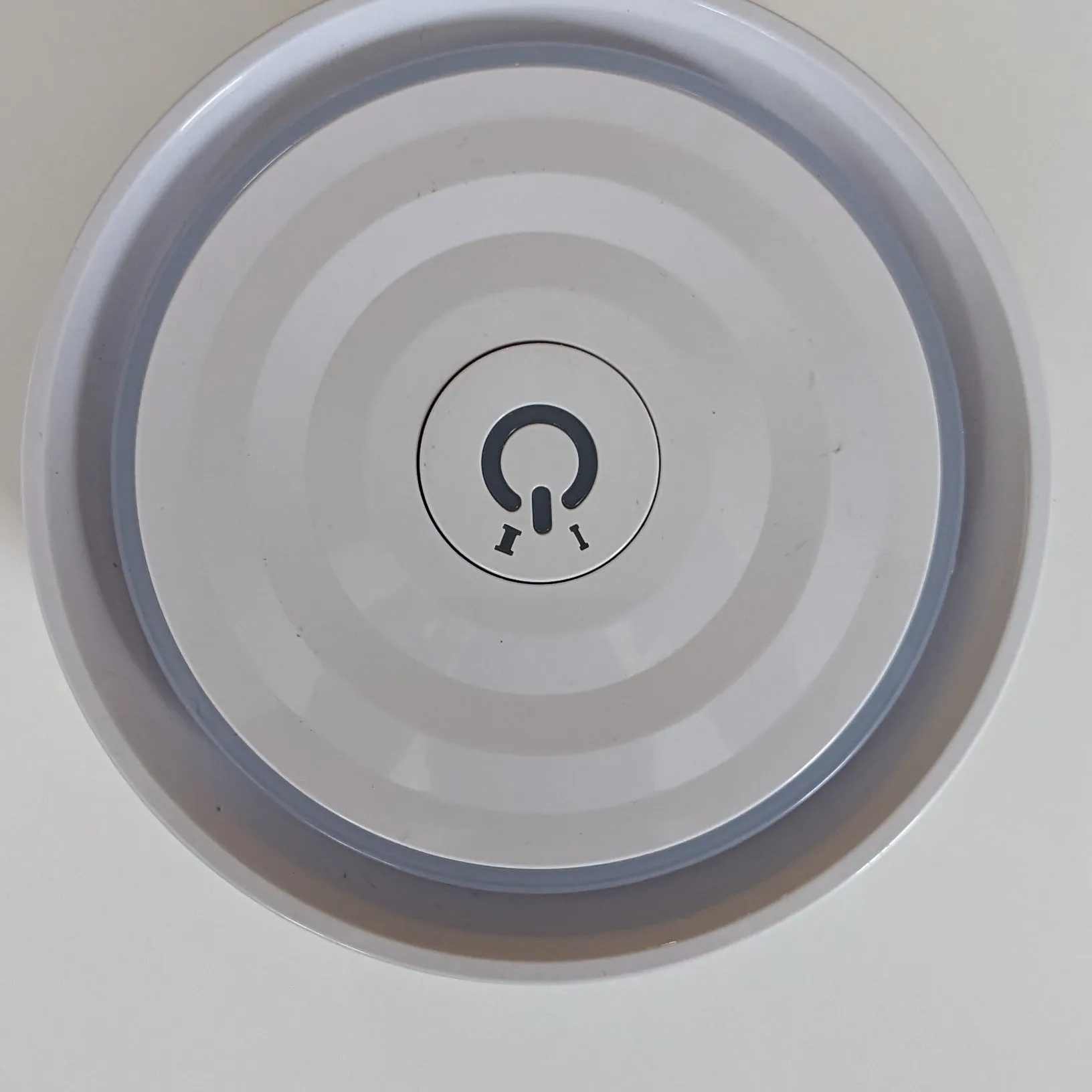 The lid from above: the touch button in the center, the light ring around the rim.