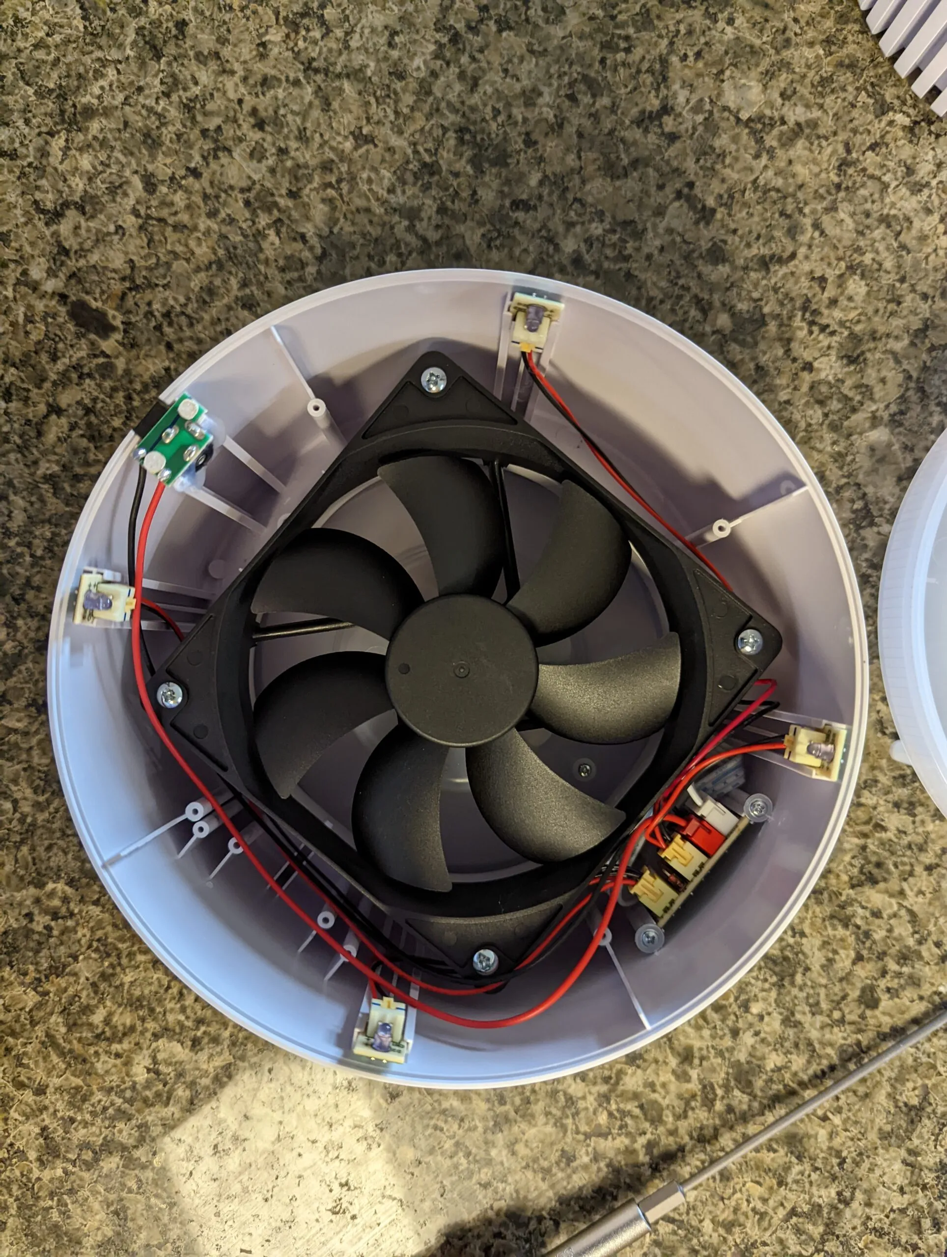 Inside the top half: a standard 120 mm PC fan ringed by the small LED boards for the base light ring, red and black wiring running to a little board on the wall.