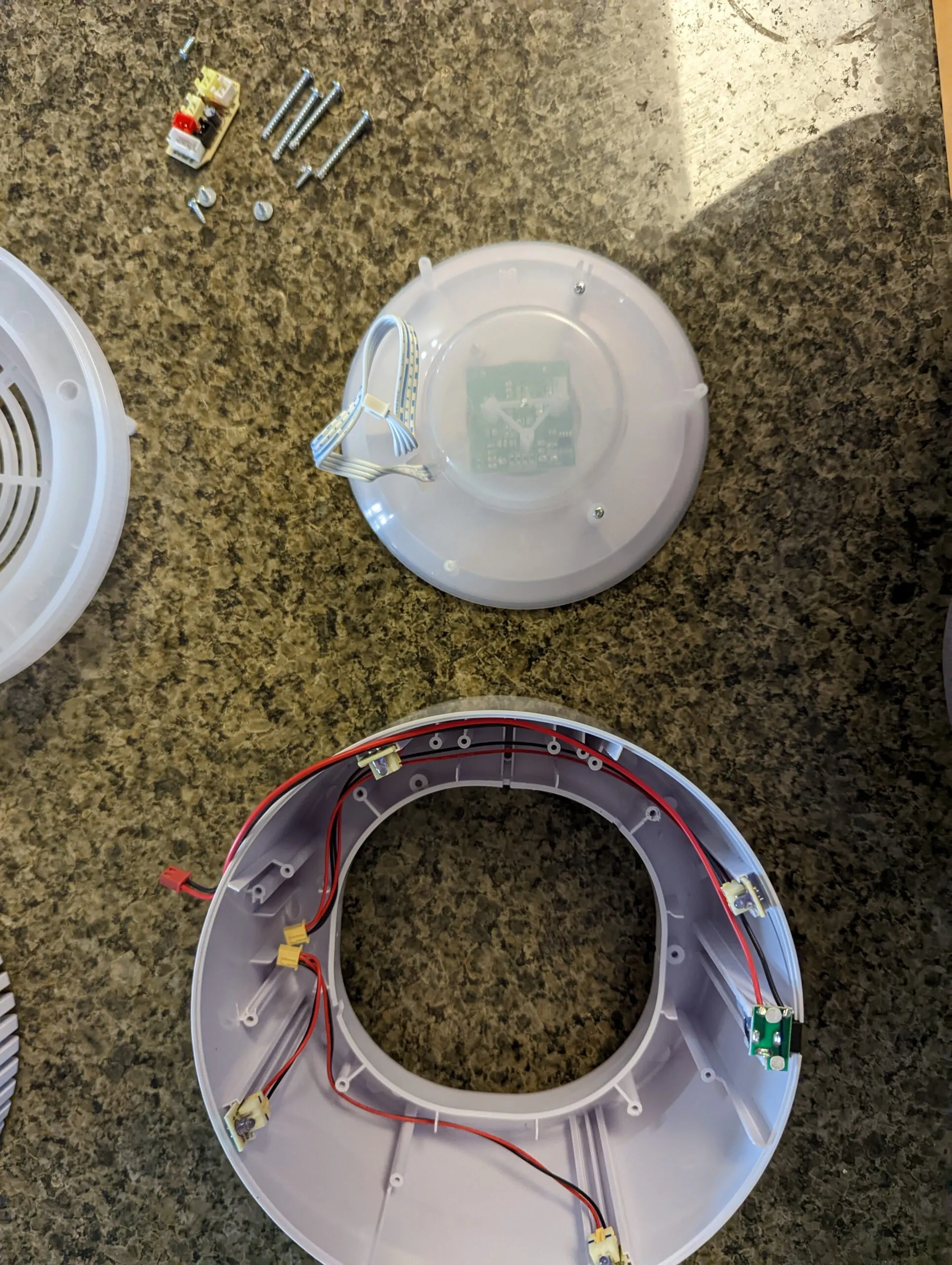 The Koios fully apart: control dome, LED ring, grille, and a pile of self-tappers.