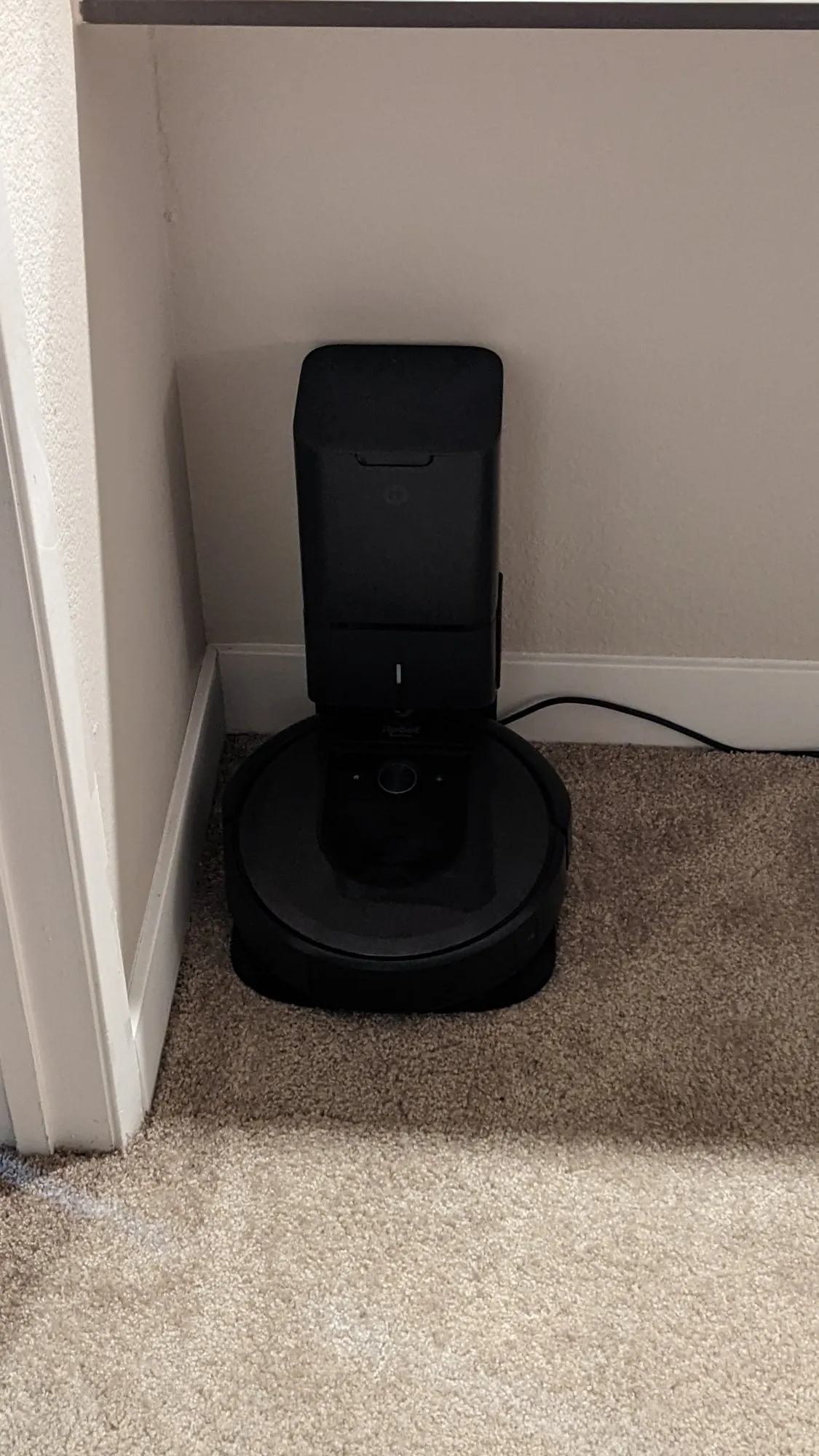 The Roomba i7 parked on its Clean Base in a carpeted alcove, August 2022.