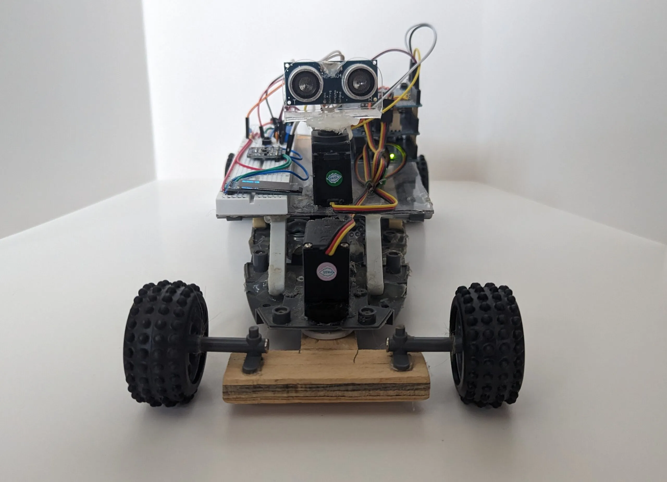 RoverBot head on: ultrasonic eyes on the head servo, steering servo beneath, LEGO wheels on the wooden axle.
