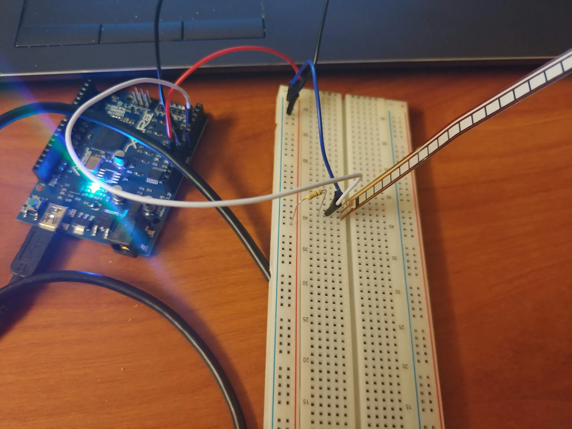 An Arduino clone beside a breadboard with a flex sensor strip wired to it, February 2019.