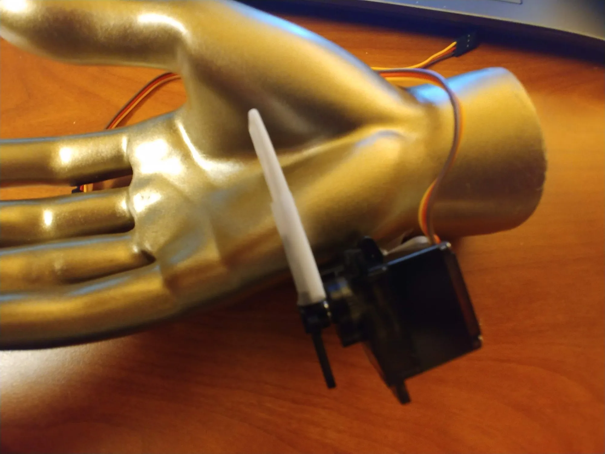 A single servo-driven printed finger clamped to the wrist of a gold mannequin hand on the bench, March 2019.