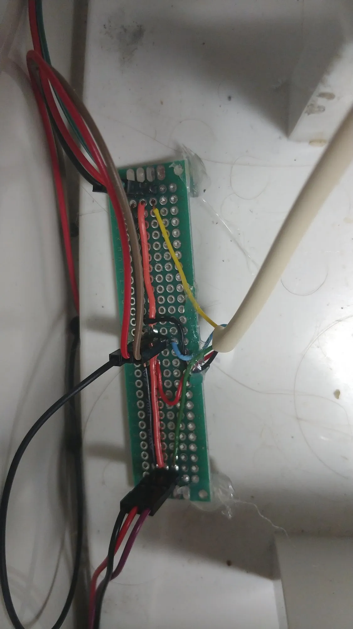 The sensor interface board, a slim perfboard hot glued inside the white appliance shell with the sensor leads running down it.